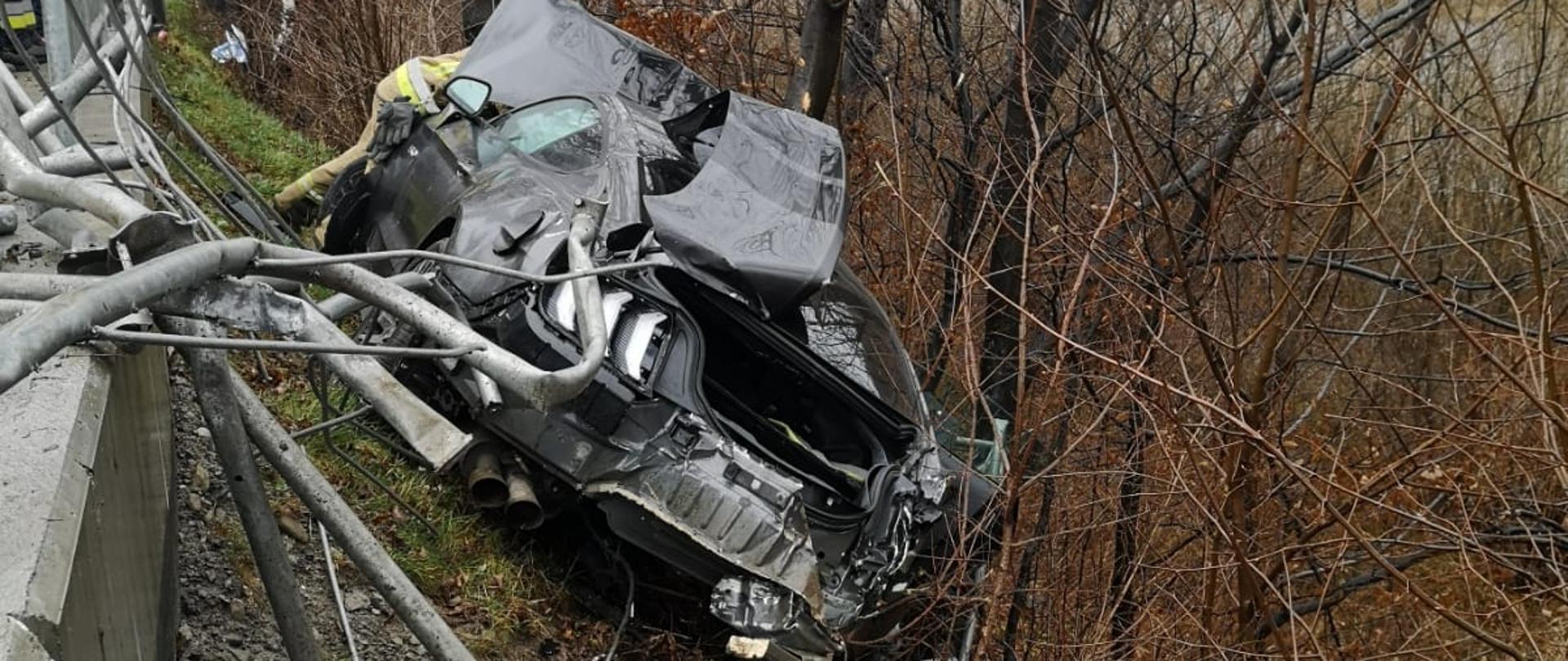 Widok samochodu osobowego na brzegu opartego o drzewa.