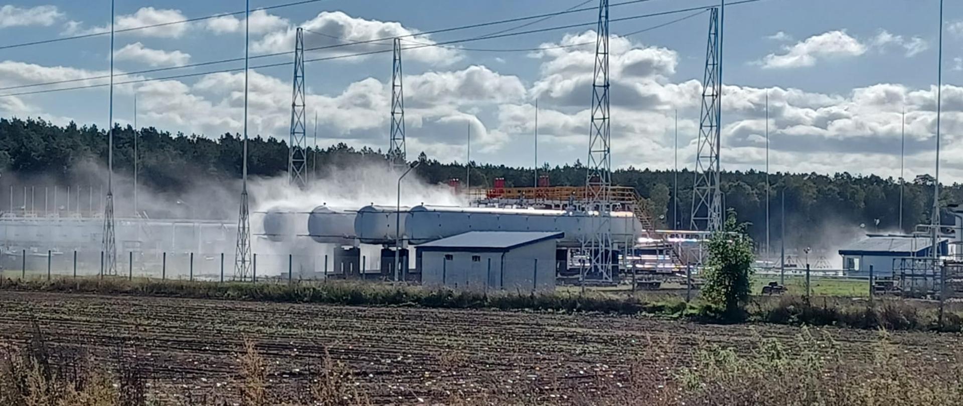 Zdjęcie przedstawia rozlewnię gazu w Nowej Niedrzwicy AmeriGas od strony północnej. Widać uruchomione zraszacze wodne nad zbiornikami, w których znajduje się płynny gaz propan.