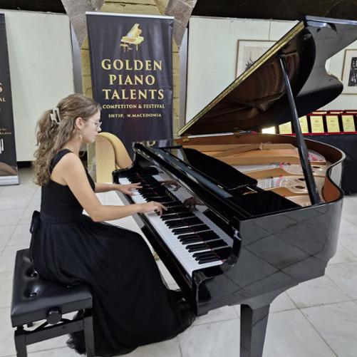 Nastolatka gra na fortepianie, w tle widoczny baner konkursu.