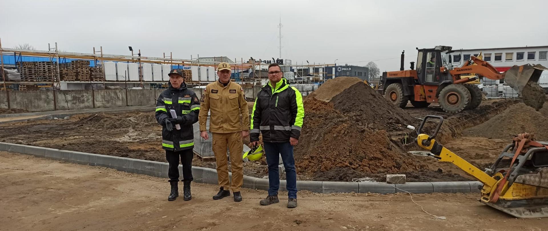 Zdjęcie przedstawia trzech mężczyzn, którzy wizytują plac budowy.