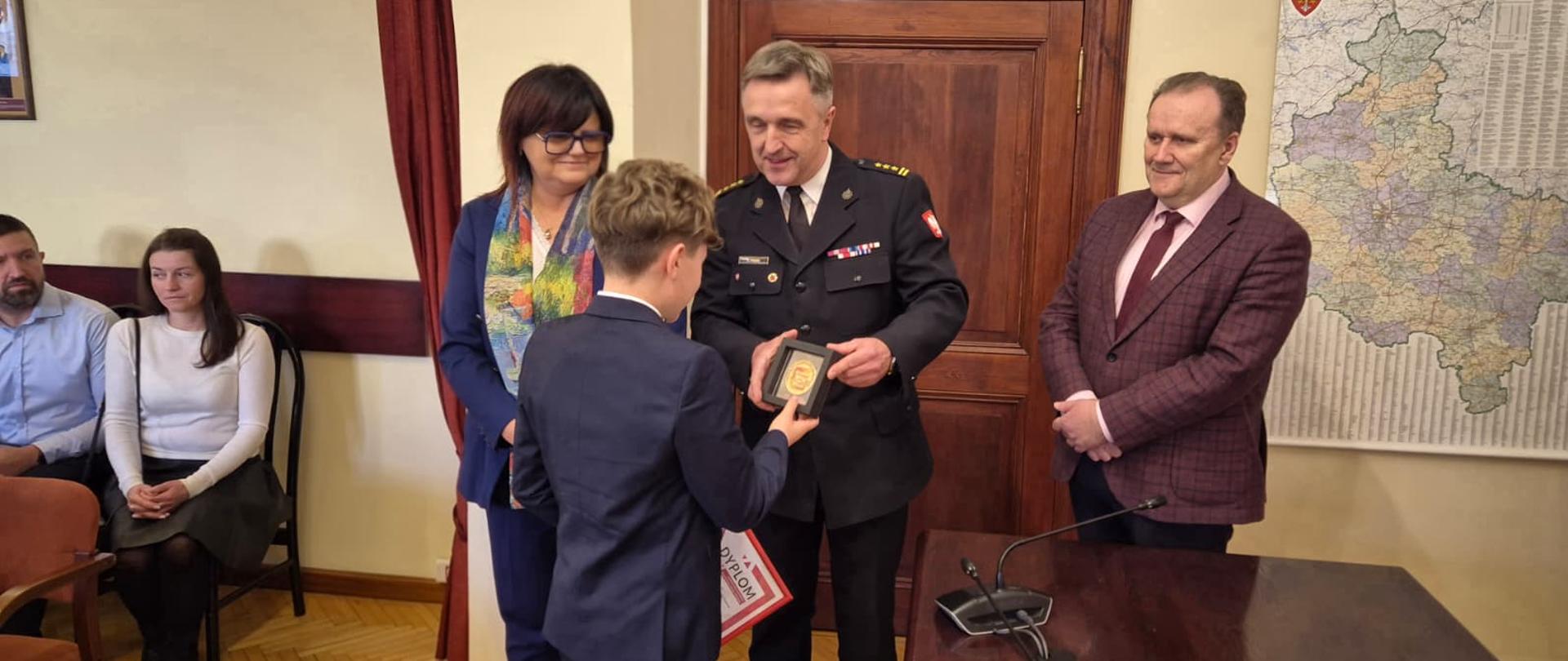 Komendanta Straży, Pani Starosta i Burmistrz Pniew wręczają odznaczenie bohaterowi