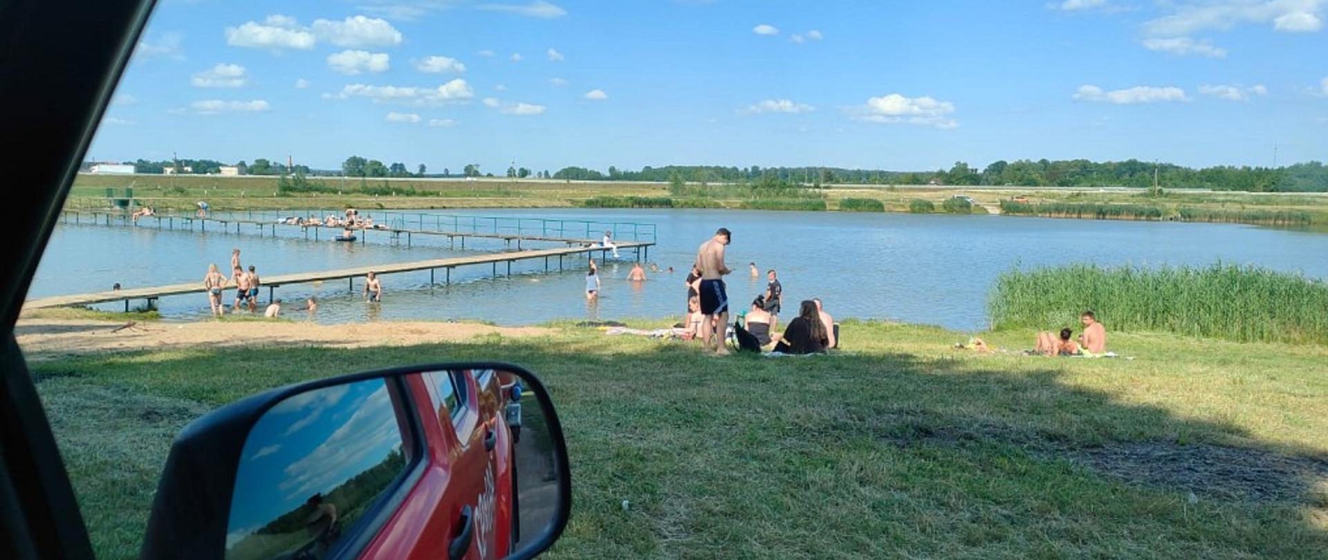 Na zdjęciu widać osoby kąpiące się nad zalewem