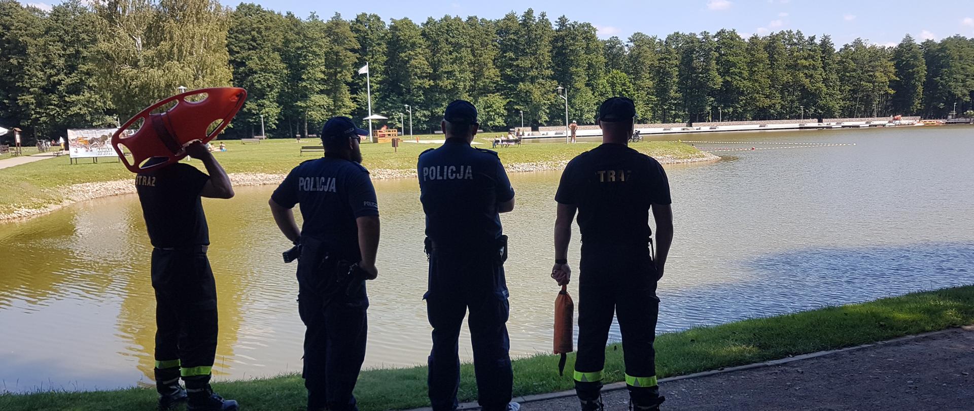 Strażacy i policjanci prowadzący patrol nad brzegiem zbiornika Gutwin