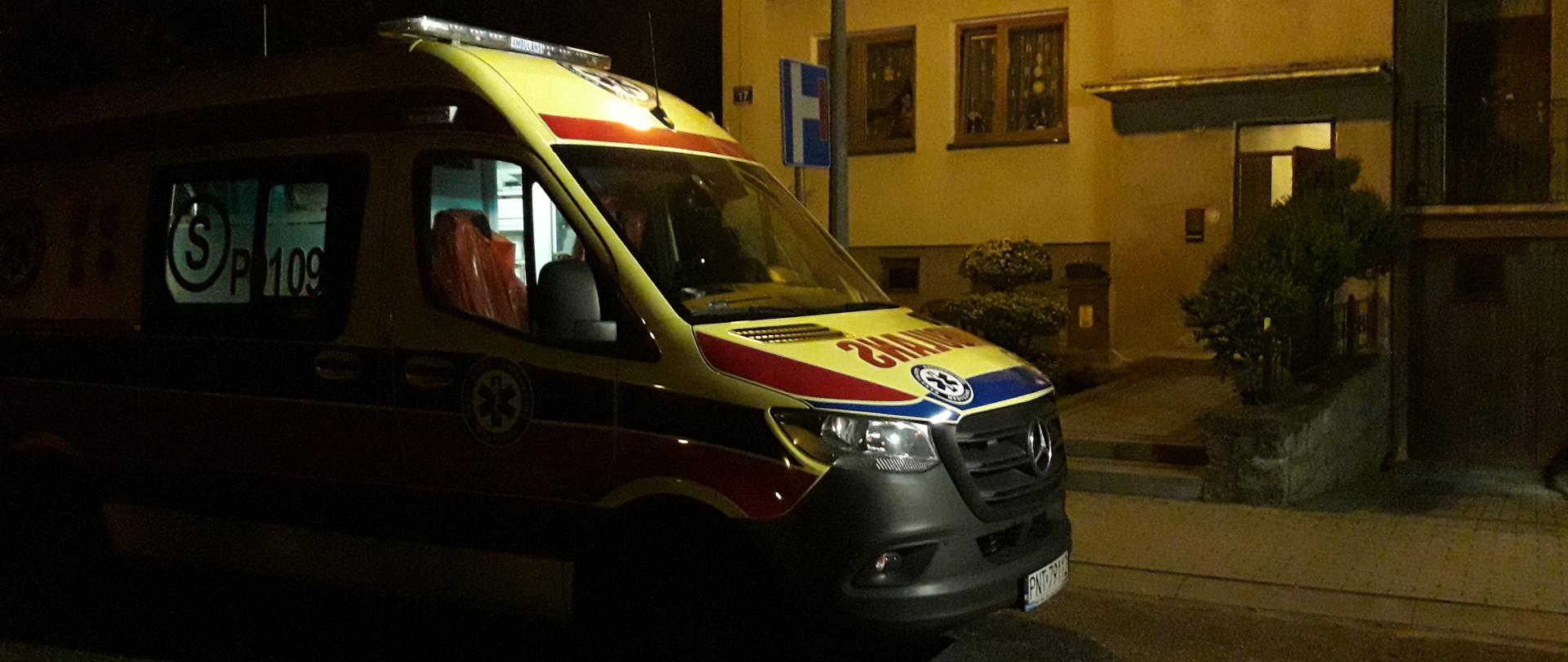 Karetka stoi pod budynkiem, noc.