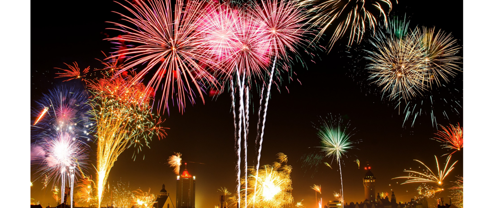 zdjęcie nocne pokazu fajerwerków na dalszym planie zabudowania miejskie