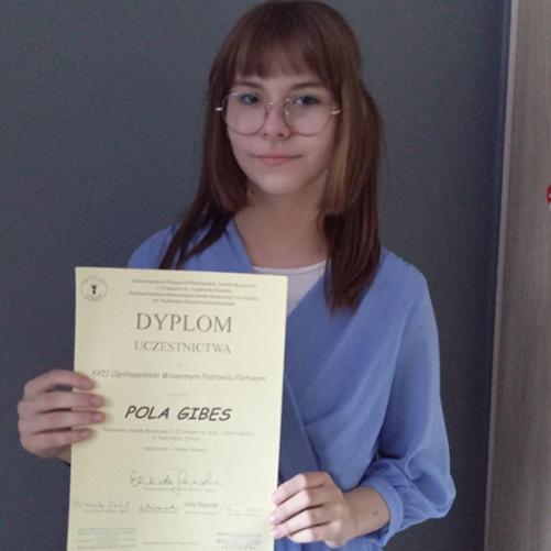 Nastolatka trzyma w rękach dyplom.