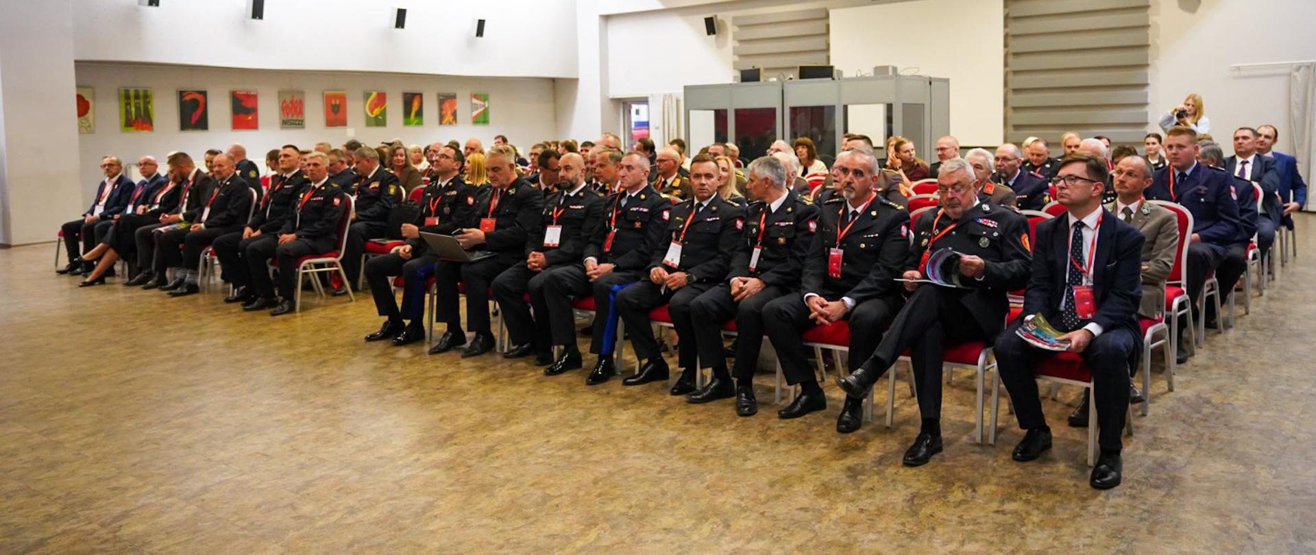 Goście przybyli na konferencję siedzący na krzesłach w sali podczas wydarzenia