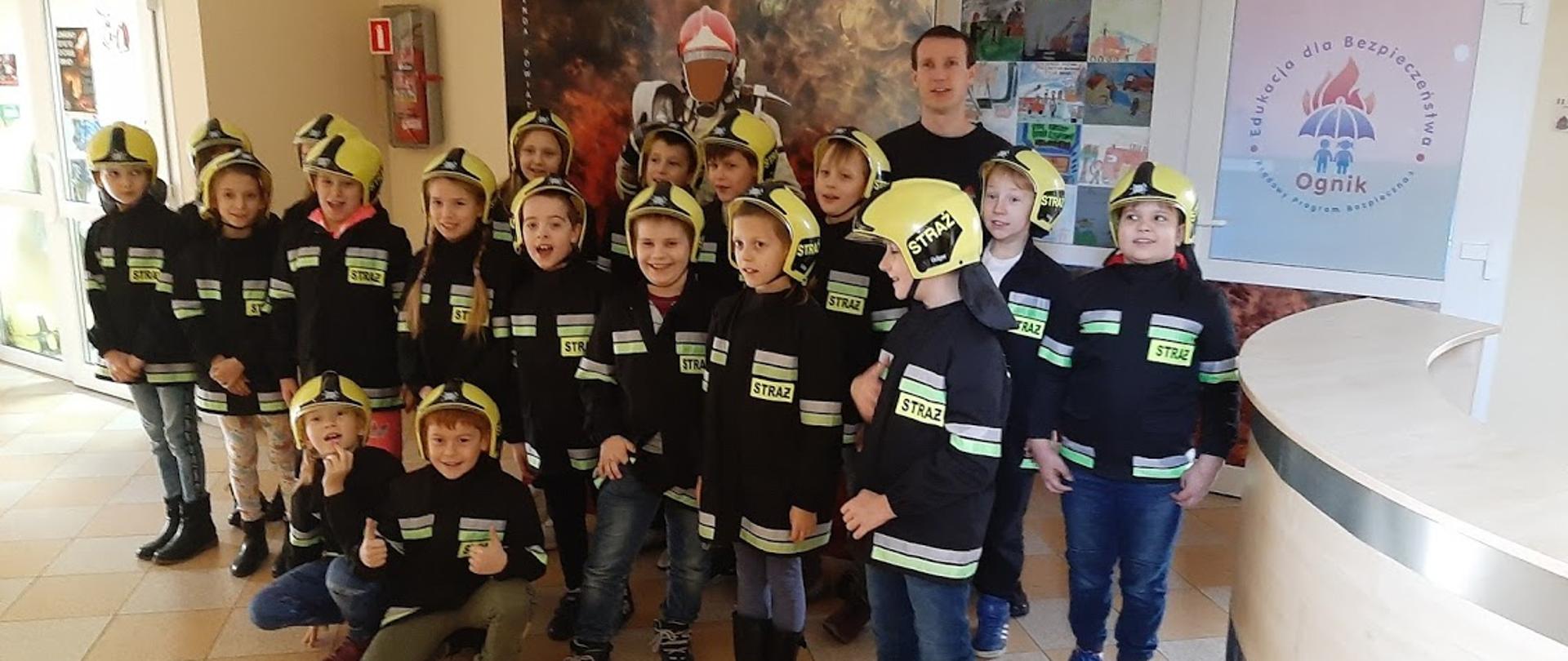 Grupka dzieci w ubraniach strażackich i chełmach
