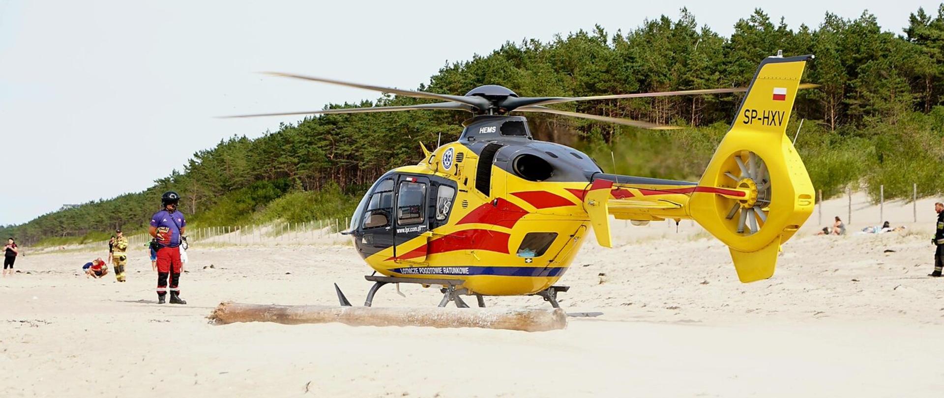 helikopter LPR który wylądował na plaży w czasie akcji ratunkowej. W tle las.