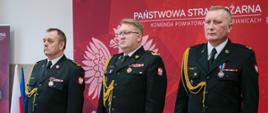 Na zdjęciu Łódzki Komendant Wojewódzki PSP w Łodzi nadbryg. Grzegorz Janowski wraz z zdającym obowiązki Komendanta Powiatowego PSP w Pabianicach st. bryg. Władysławem Durajem oraz mł. bryg. Jackiem Karczem, któremu ŁKW PSP w Łodzi powierzył pełnienie obowiązków Komendanta Powiatowego PSP w Pabianicach. Strażacy występują w umundurowaniu wyjściowym ze sznurem. Zdjęcie wykonane na Stali tradycji KP PSP w Pabianicach.