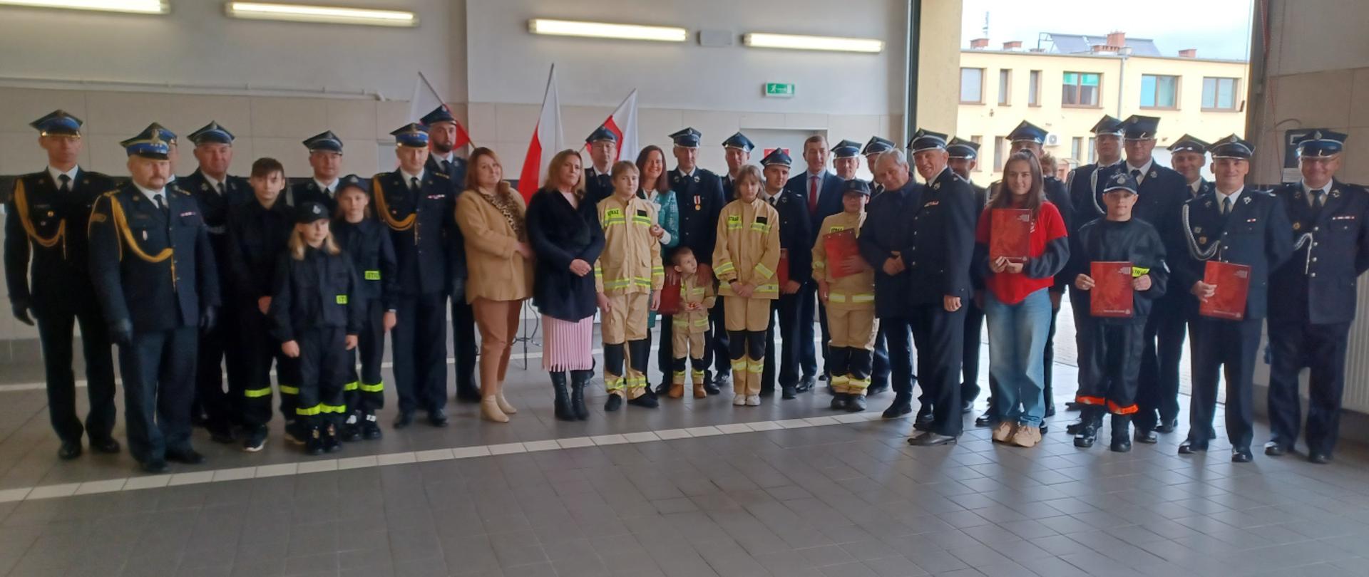 Uczestnicy uroczystości związanej z przekazaniem promes dofinansowania dla Młodzieżowych Drużyn Pożarniczych powiatu głubczyckiego na zdjęciu grupowym