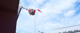 Widać flagę państwową, która powiewa na wysokości, jest przymocowana do podnośnika straży pożarnej