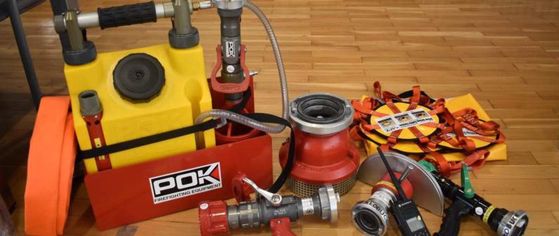 Zdjęcie przedstawia węże pożarnicze, prądownicę, wytwornicę piany, kurtynę wodną, smok ssawny, zabezpieczenia na kierownicę (stosowane w ratownictwie drogowym), radiotelefon przenośny.