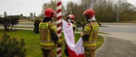 Trzech strażaków mocujących flagę do masztu