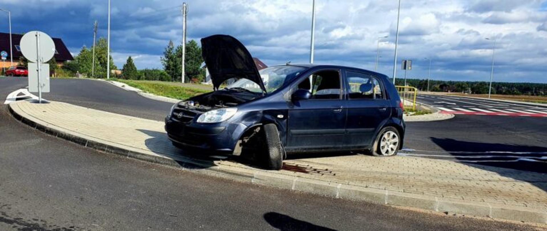 Widać uszkodzony samochód od przodu, podniesiona maska