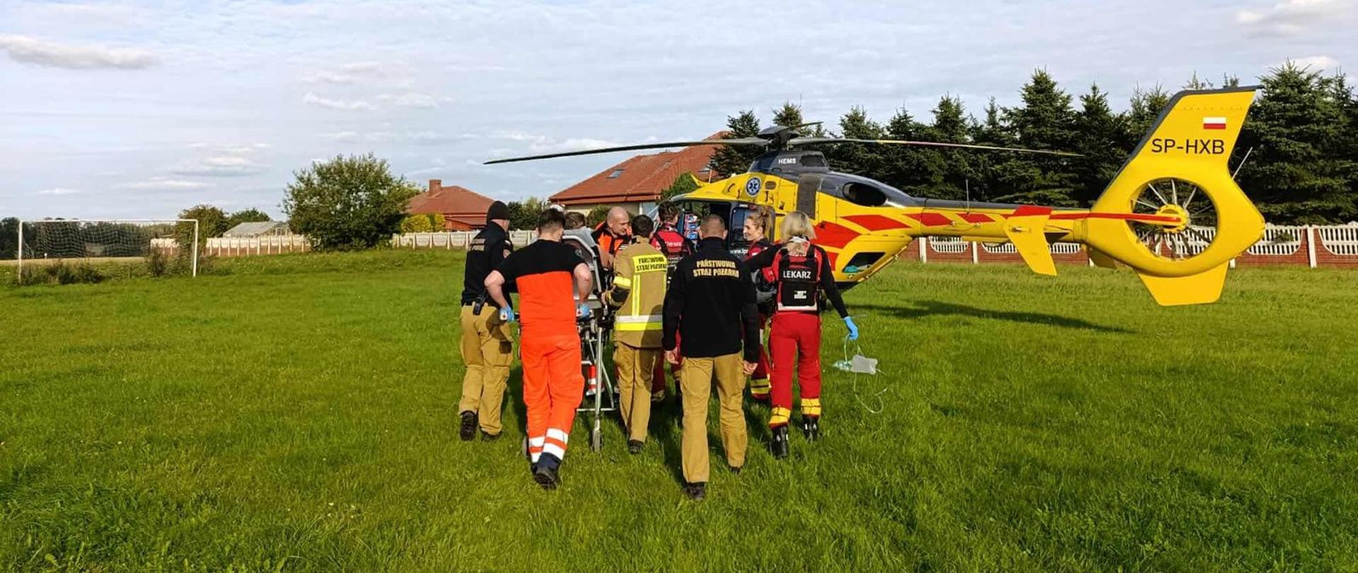 Strażacy, zespół PRM i LPR transportują poszkodowanego