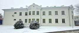 Zdjęcie budynku Prokuratury Rejonowej w Łukowie po remoncie. Kremowa elewacja z dwiema kondygnacjami. Parking przysypany śniegiem.