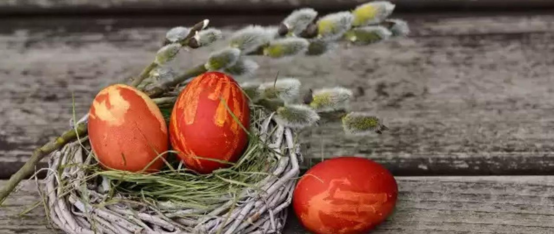 Na zdjęciu akcenty świąt wielkanocnych, malowane jajka, gniazdo z sianem oraz palma. 
