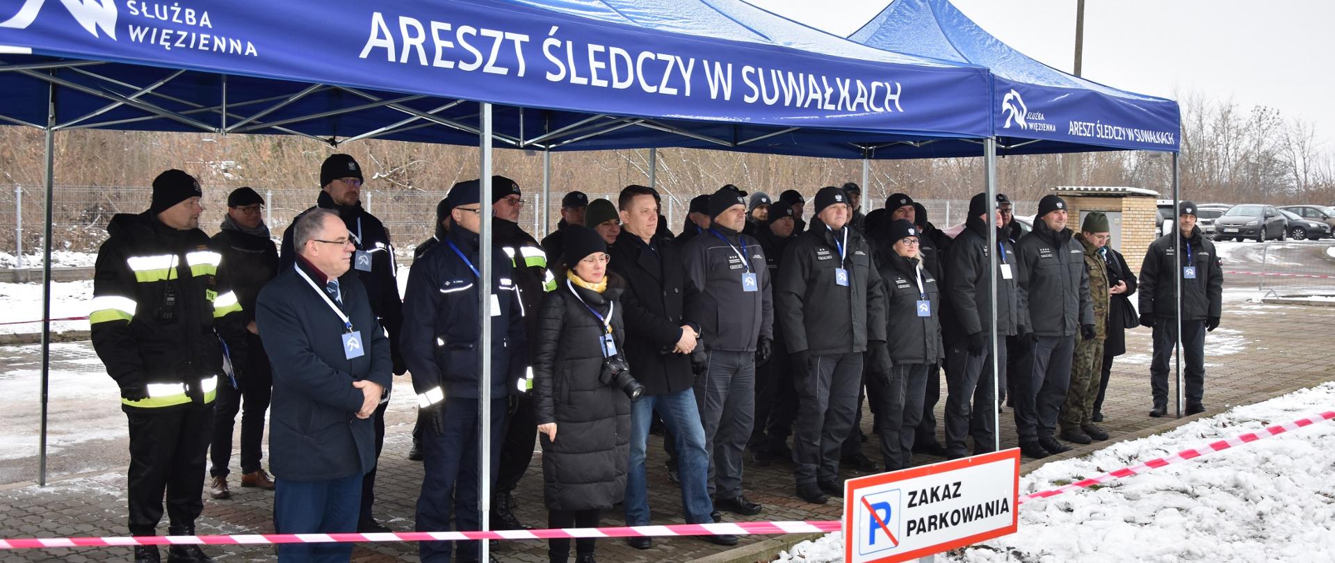 Zaproszeni goście stoją pod namiotem