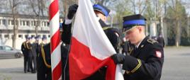Strażacy pocztu sztandarowego mocują flagę RP na maszcie, aby możliwe było jej uroczyste wciągnięcie