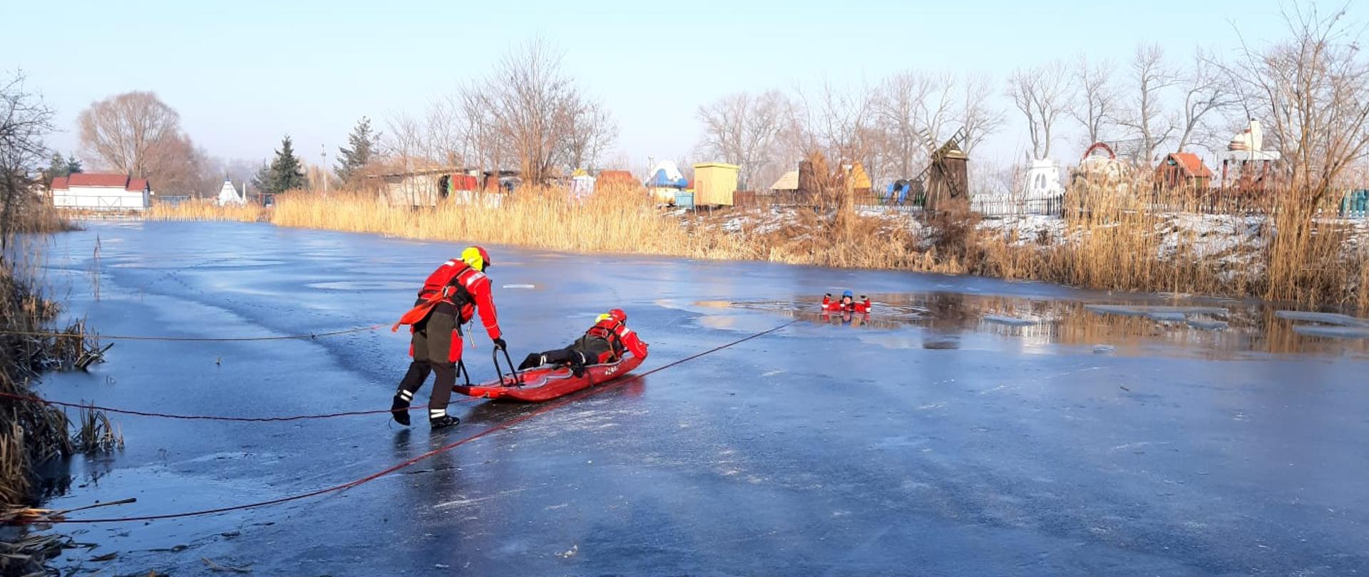 SZKOLENIE DOSKONALĄCE W ZAKRESIE RATOWNICTWA LODOWEGO. akwen wodny, pokryty warstwą lodu, strażacy ćwiczą w zakresie ratownictwa wodnego działania na zamarzniętych zbiornikach.