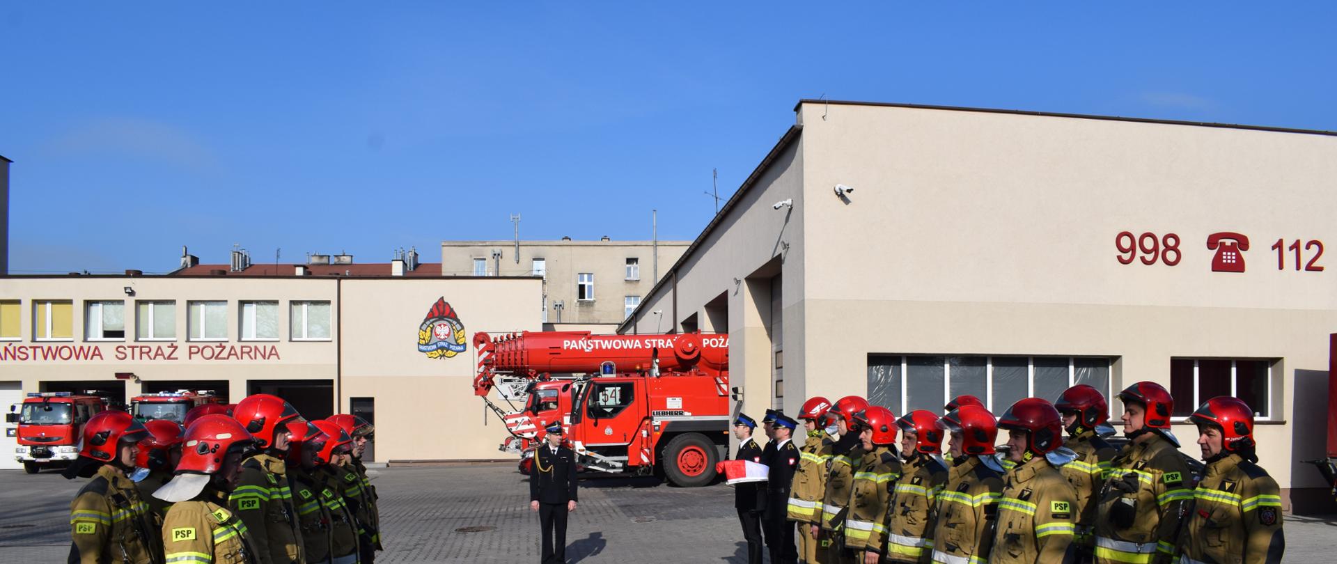 Widok uczestników zbiórki na placu JRG Tczew, podczas uroczystego podniesienia flagi państwowej.