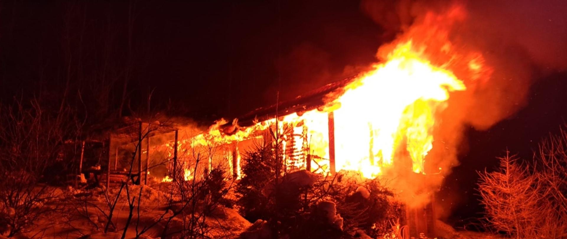 Pora nocna. Widok na stojący w płomieniach budynek.