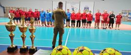 Mistrzostwa Województwa Strażaków w halową piłkę nożną ceremonia zakończenia zawodów. strażacy sportowcy na zbiórce w hali. Na pierwszym tle puchary i piłki.
