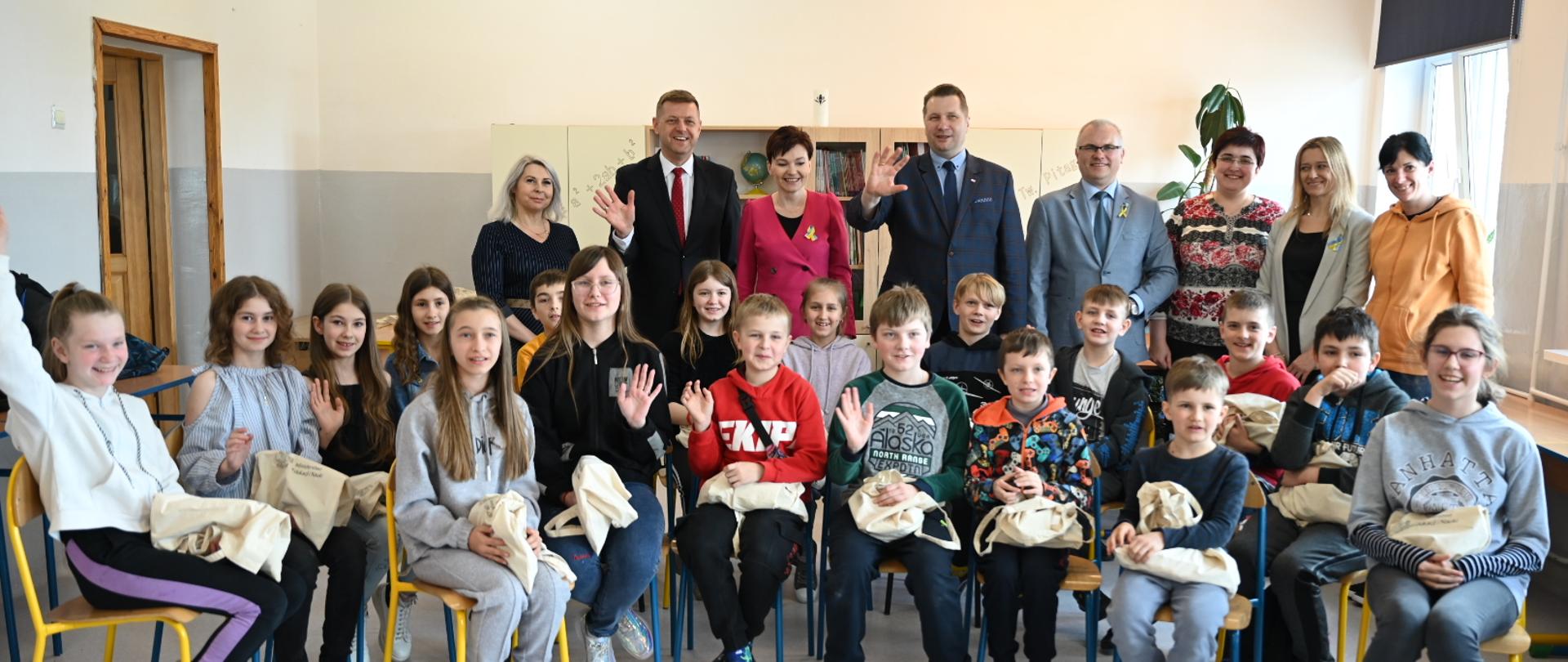 Zdjęcie zbiorowe, uczniowie siedzą na krzesłach, za nimi stoją nauczyciele i minister Czarnek.