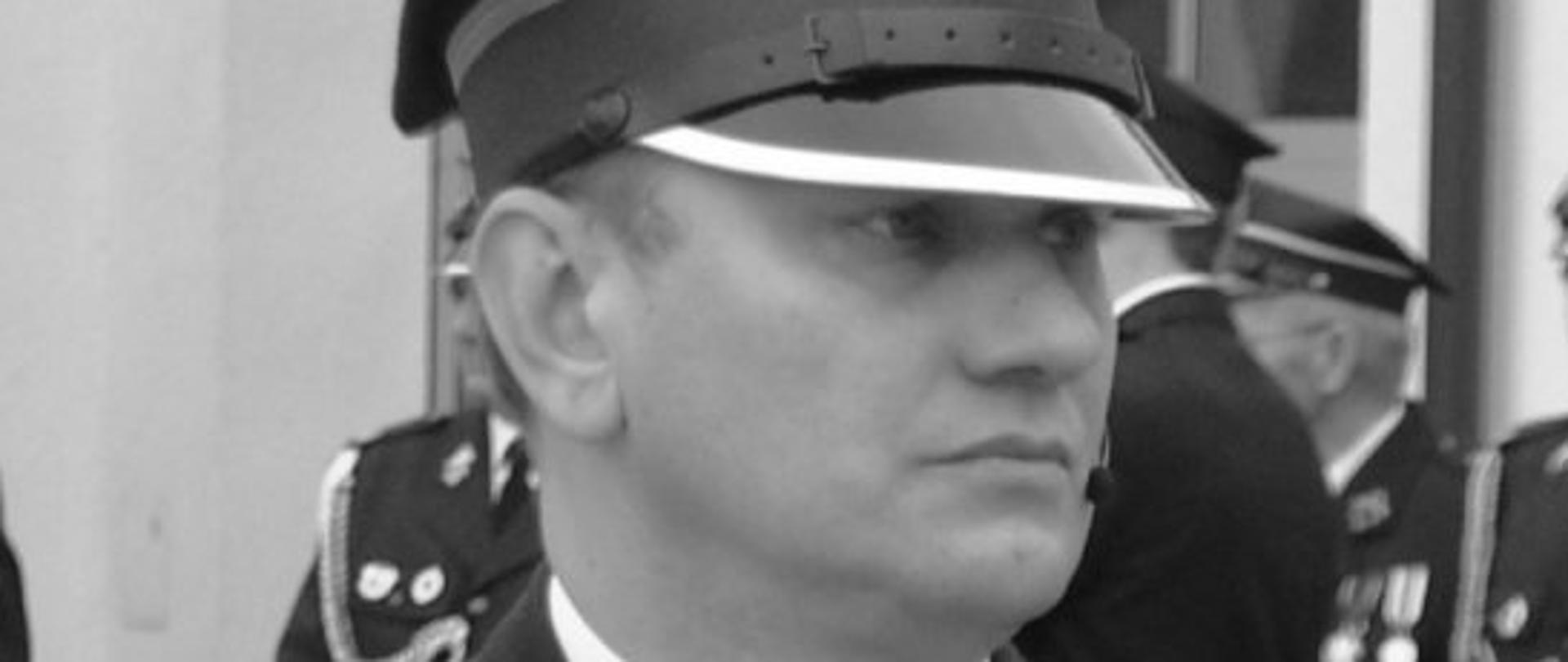 czarno-białe zdjęcie strażaka w okularach, w rogatywce, w mundurze w białej koszuli z krawatem
