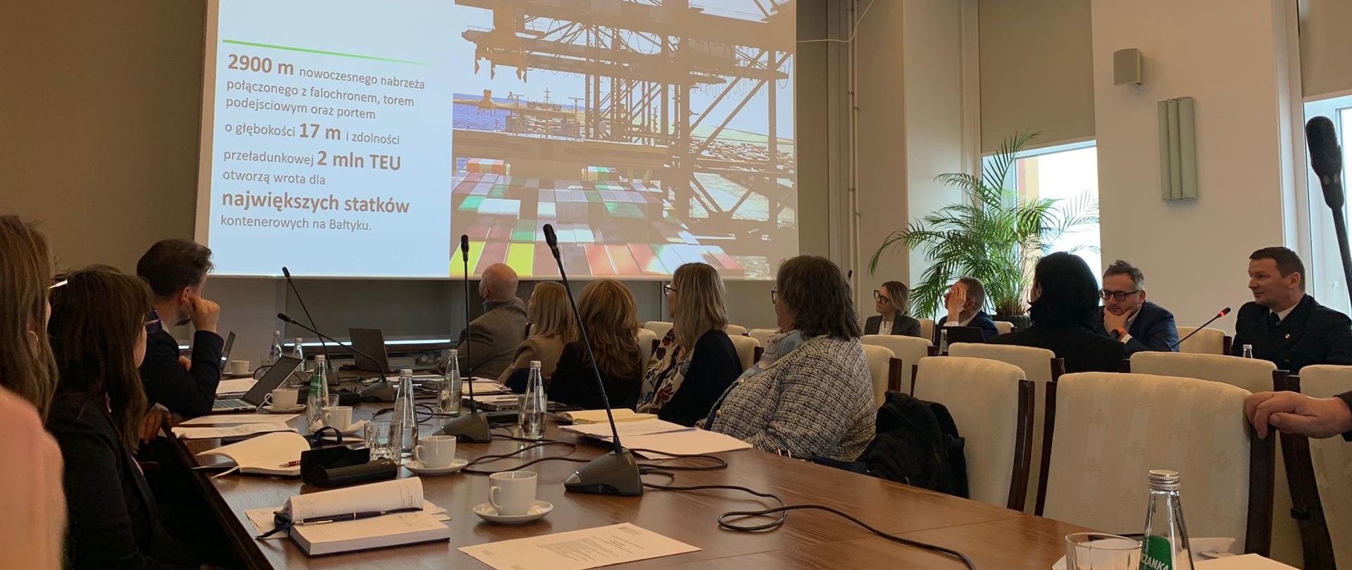 na sali siedzą ludzie, widzimy tył ich głów, patrzą na wyświetlaną prezentację