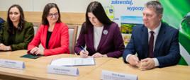 Wiceministra klimatu i środowiska Anita Sowińska bierze udział w podpisaniu umowy między WFOŚiGW w Łodzi a gminą Zgierz. Przy stole zasiadają wiceministra, Wójt Gminy Zgierz i Prezes WFOŚiGW w Łodzi. 