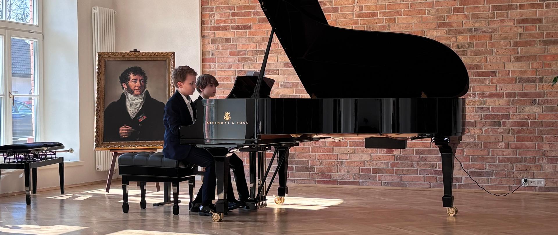 Sceny z konkursu muzycznego w sali koncertowej: uczniowie grający na fortepianie w duetach, wystąpienia organizatorów oraz wręczenie nagród dzieciom. Na zdjęciach widoczna jest publiczność siedząca na widowni oraz elegancko ubrani uczestnicy i nauczyciele na scenie z fortepianem.