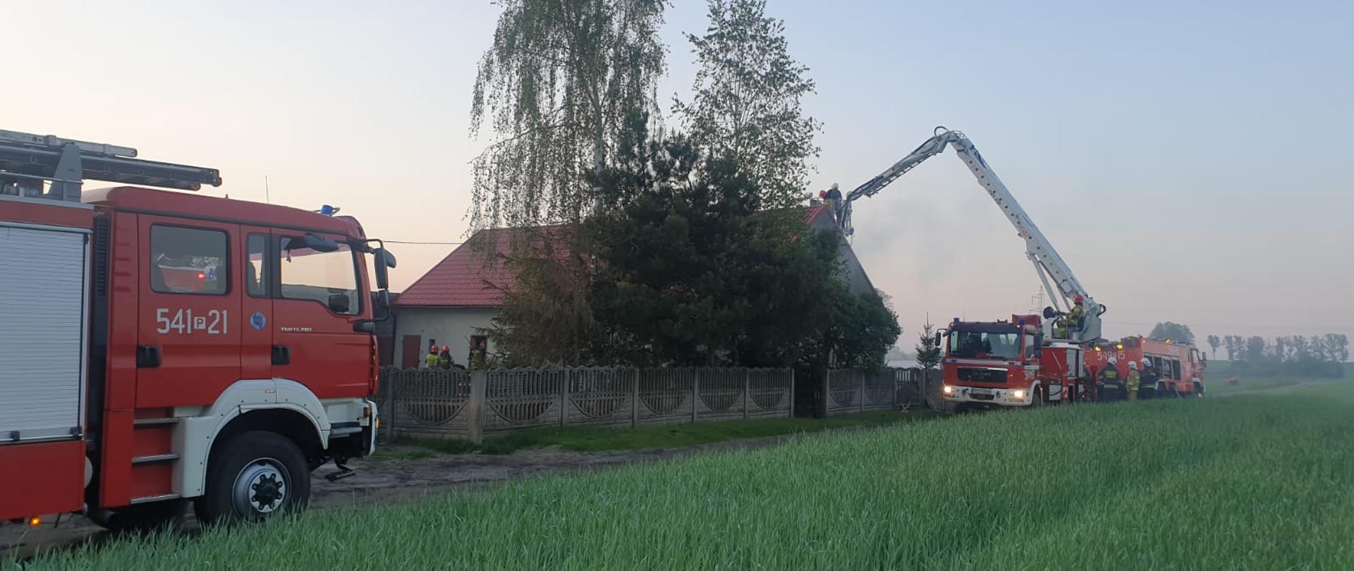 Strażacy w trakcie gaszenia pożaru w budynku mieszkalnym. Do działań został użyty podnośnik hydrauliczny.