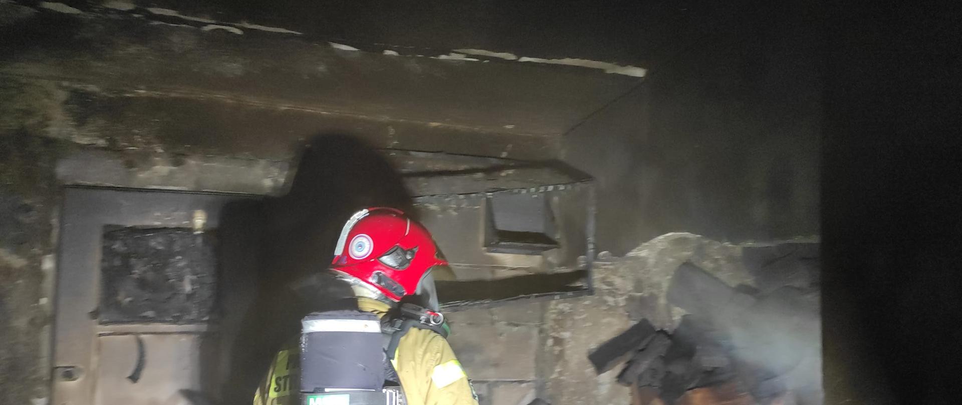 Widać strażaka w kotłowni, jest ciemno