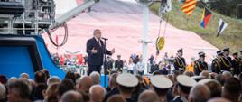 Minister infrastruktury Andrzej Adamczyk na tle statku Zodiak II w trakcie otwarcia Kanału żeglugowego przez Mierzeję Wiślaną