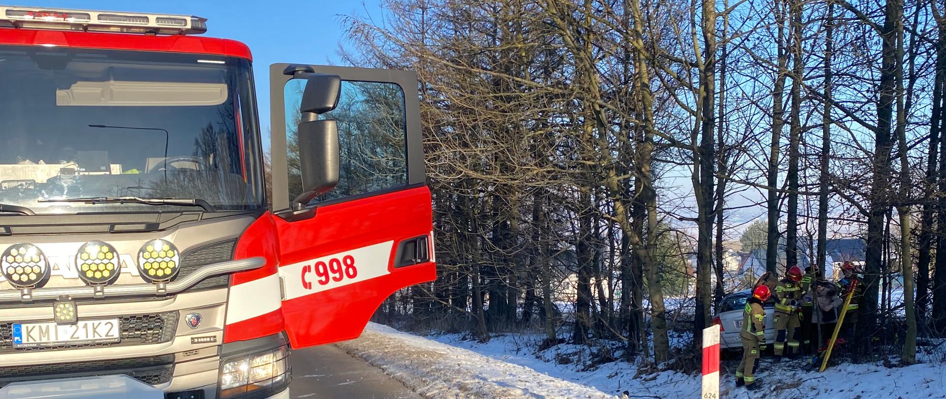 Na zdjęciu wóz strzacki na jezni w rowie wrak samochodu osobowego oraz strazacy