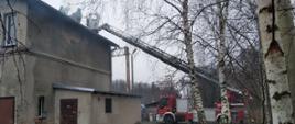 Widoczne miejsce zdarzenia oraz strażacy działający na dachu budynku.
