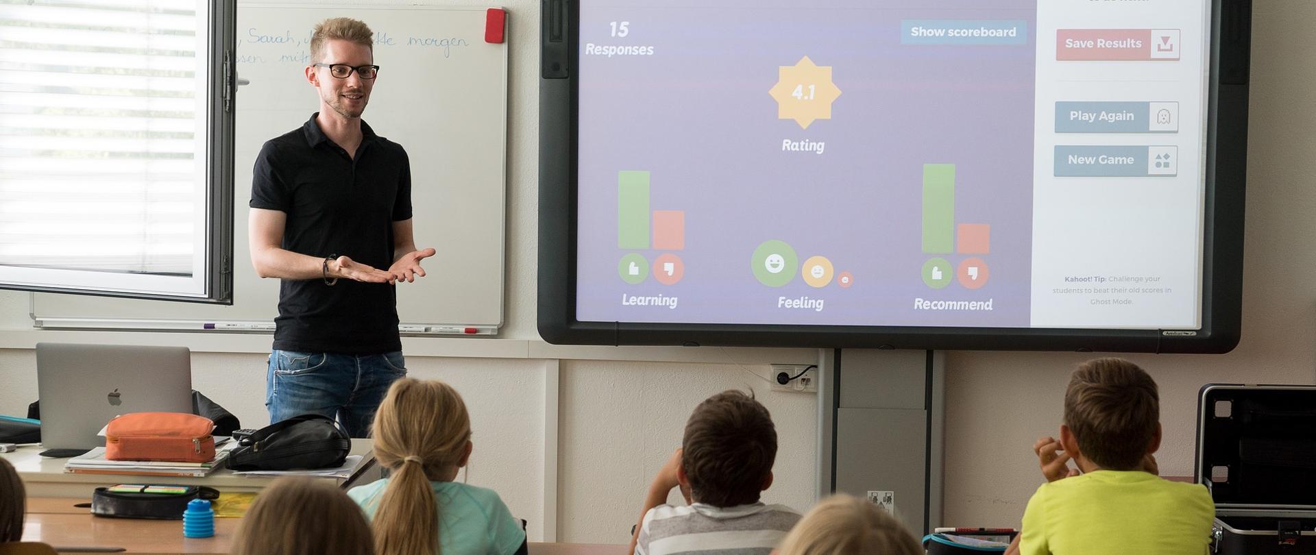 Nauczyciel w trakcie zajęć w szkole podstawowej tłumaczący coś dzieciom w klasie