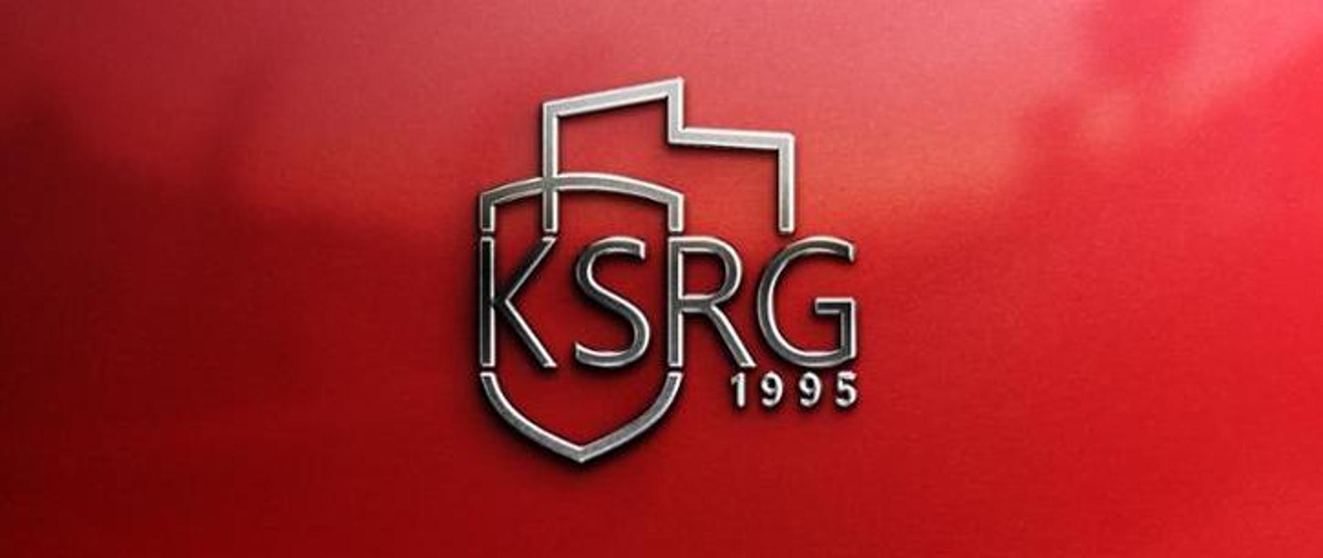 Wprowadzenie do stosowania logo krajowego systemu ratowniczo - gaśniczego. Na czerwonym tle srebrny napis KSRG 1995