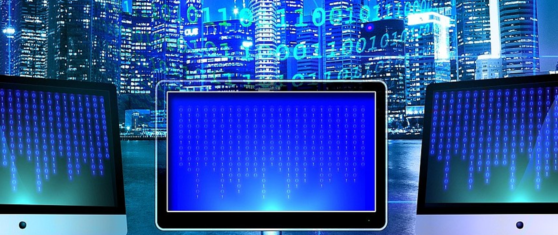 trzy monitory, w tle wysokie budynki miasta, kolorystyka niebieska