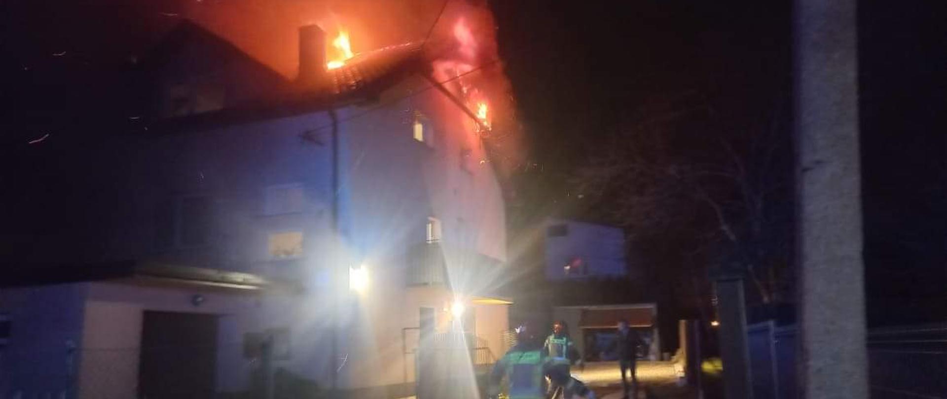 Na zdjęciu widać pożar dachu na budynku mieszkalnym oraz strażaków