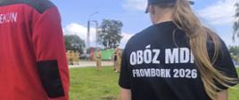 Na zdjęciu dwoje druhów MDP stoi tyłem na ich plecach napisy nazwy obozu OBÓZ MDP FROMBORK 2026