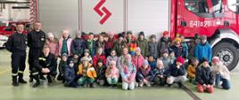 Odwiedziny strażnicy i sali edukacyjnej „Ognik” w KP PSP w Sokołowie Podlaskim 20.03.2024 r. - wspólne zdjęcie w garażu na tle samochodu strażackiego