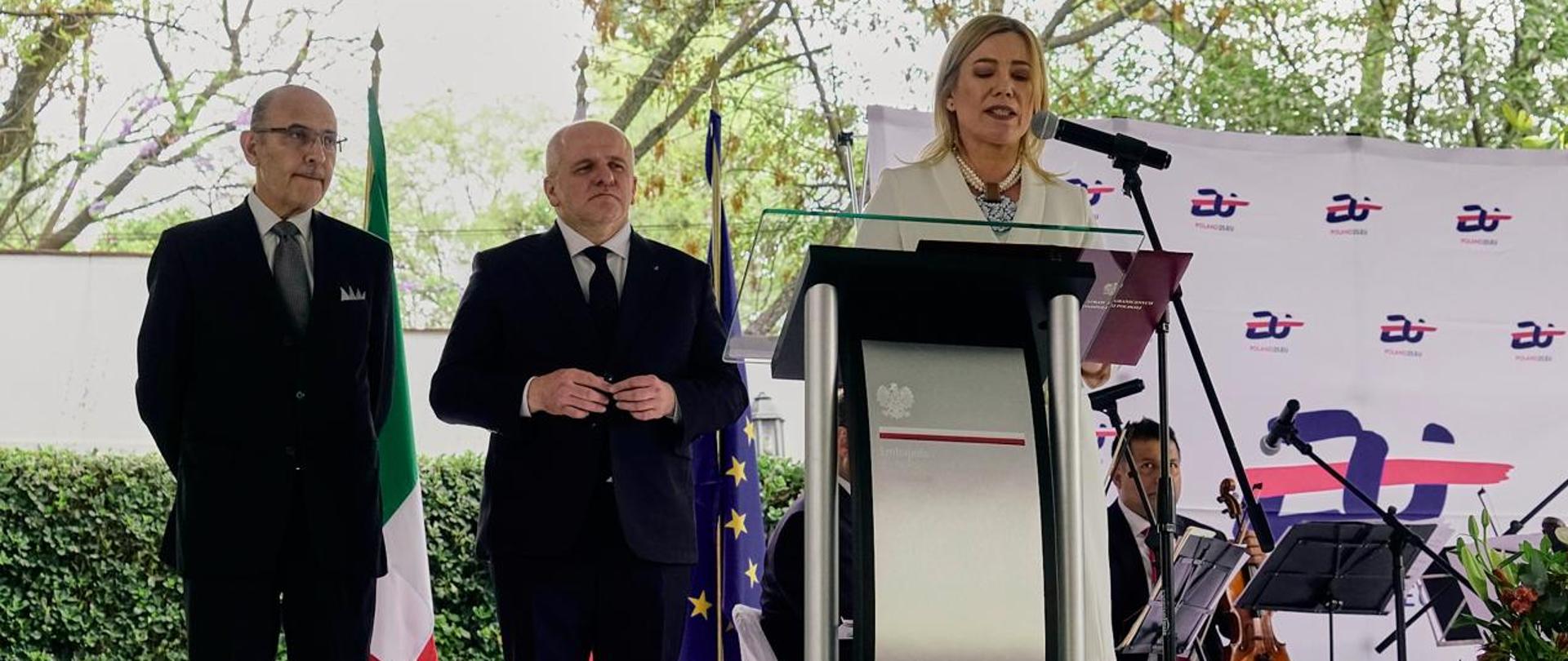 Junto al atril al aire libre se encuentra la Embajadora de Polonia en México, Agnieszka Frydrychowicz-Tekieli. Al fondo, el diputado Paweł Kowal y Octavio Tripp Villanueva, director general para Europa de la Secretaría de Relaciones Exteriores de México.