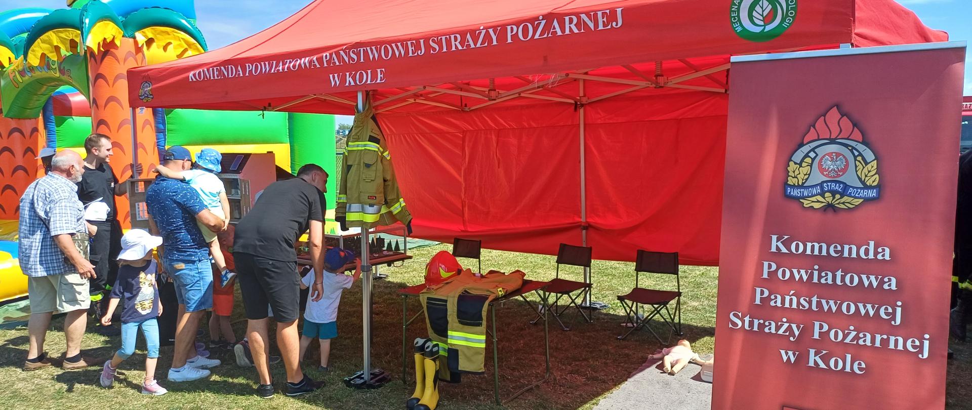 Zdjęcie przedstawia uczestników Pikniku Wojskowego w Dąbiu przy stoisku Komendy Powiatowej Państwowej Straży Pożarnej w Kole