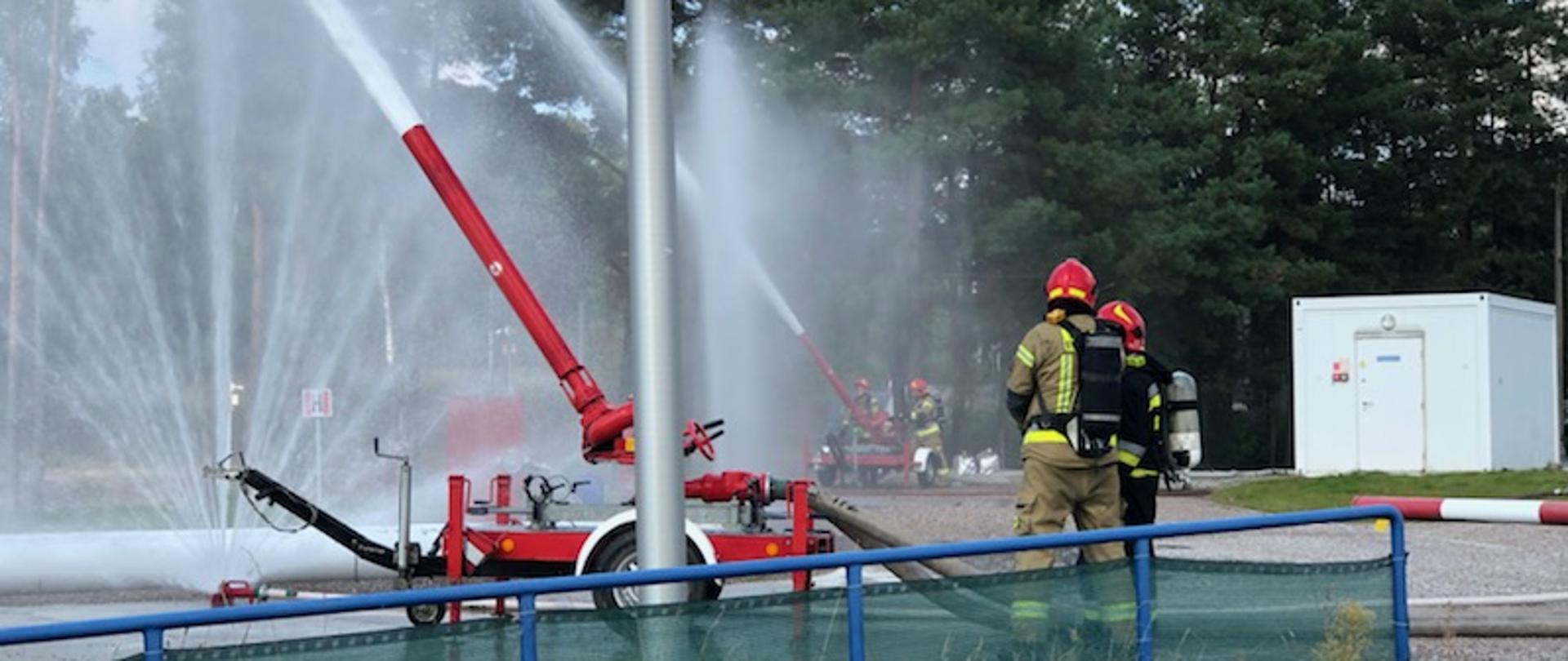Na zdjęciu widać dwa działka wodno pianowe ustawione podczas podawania wy na zbiornik z paliwem