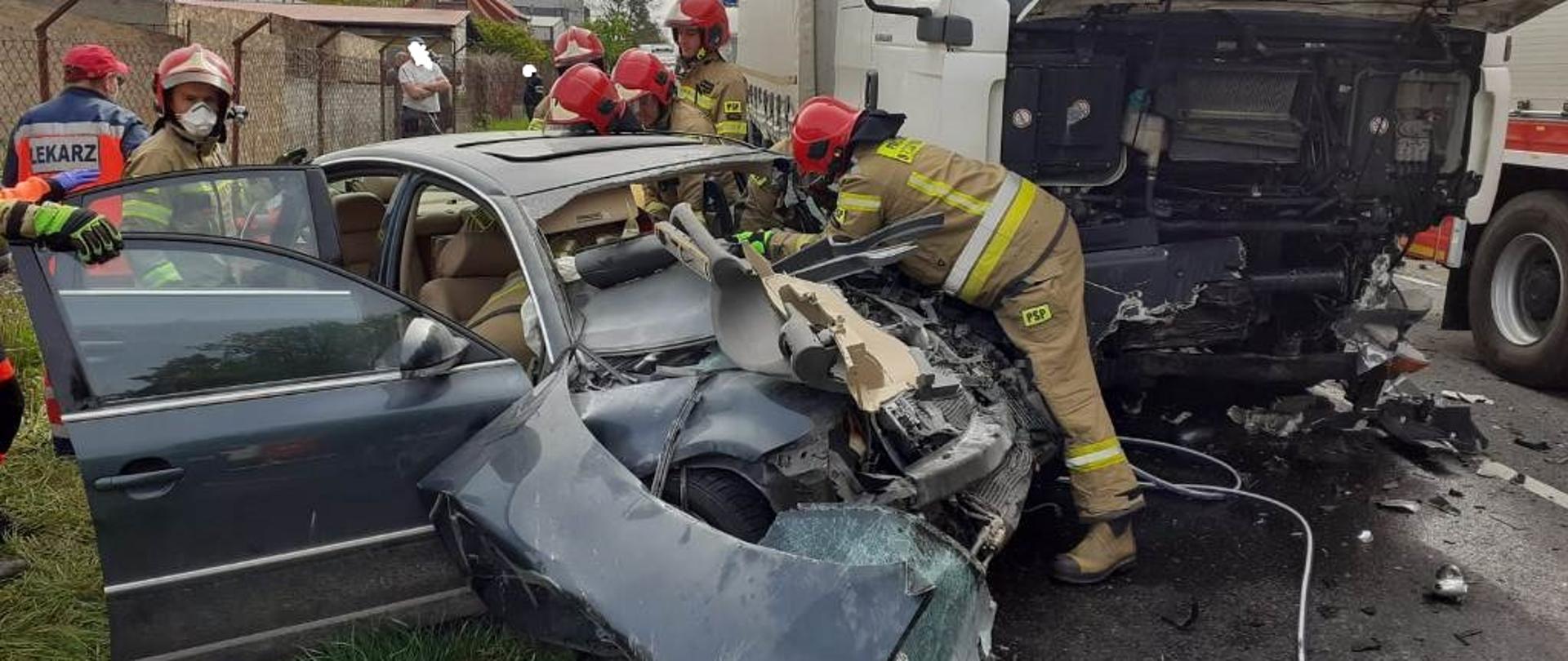 Strażacy wykonują dostęp do poszkodowanej kobiety, która została uwięziona w samochodzie po wypadku.