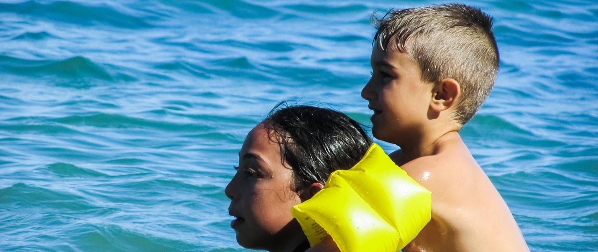 dwoje dzieci zanurzone w wodzie patrzący w lewą stronę