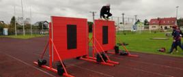 Stadion sportowy, strażak pokonujący ścianę podczas jednej z konkurencji